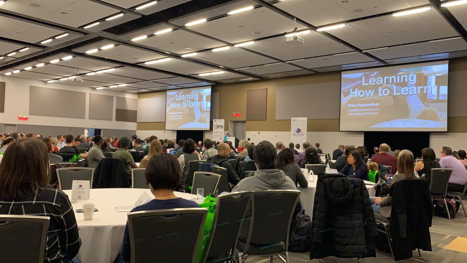 GOAT 2018 keynote room with attendees facing two projection screens
